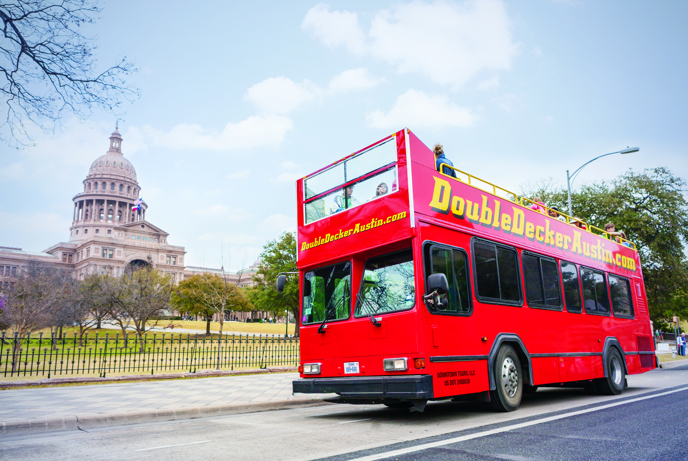 Double Decker Austin Tour Bus parked outside of the Texas State Capitol grounds